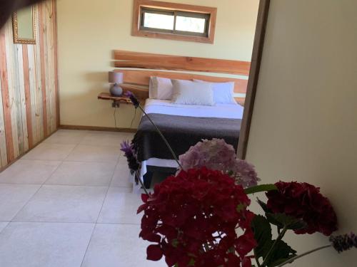 a bedroom with a bed with a mirror and flowers at Viejoboldo_latrinchera in Los Rábanos