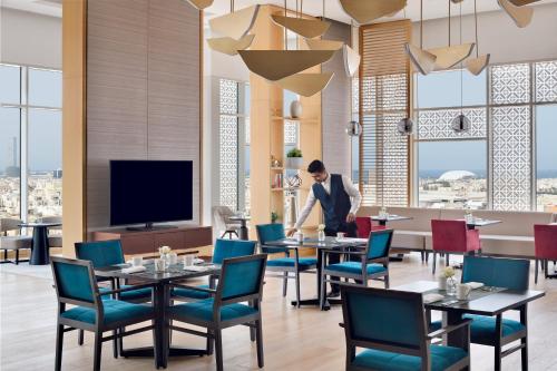 a man standing in a restaurant with tables and chairs at Crowne Plaza - Jeddah Al Salam by IHG in Jeddah