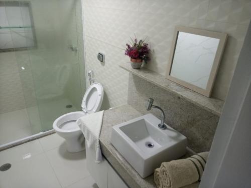 La salle de bains est pourvue d'un lavabo, de toilettes et d'un miroir. dans l'établissement Apart Hotel Marinas Vista para o Mar Praia dos Carneiros, à Tamandaré