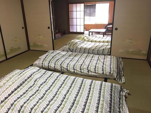 rząd czterech łóżek w pokoju w obiekcie ゲストハウスさくら Guesthouse Sakura w mieście Sukumo