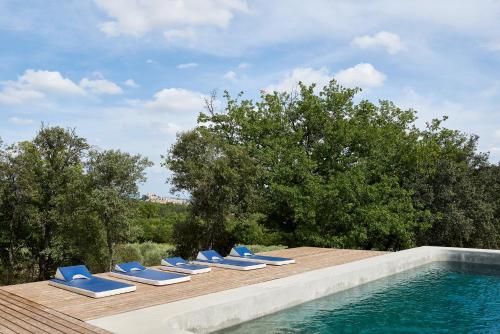 un grupo de tumbonas azules junto a una piscina en Domaine La Ferme HI bride, en Villelaure