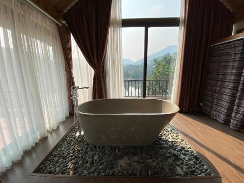 uma banheira num quarto com uma grande janela em Thang Mây Village Rersort em Ba Vì