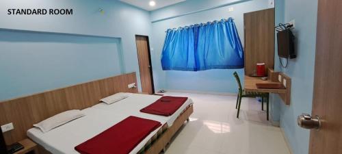 een slaapkamer met een bed, een bureau en een televisie bij Hotel Aaditya Palace in Bhusāwal