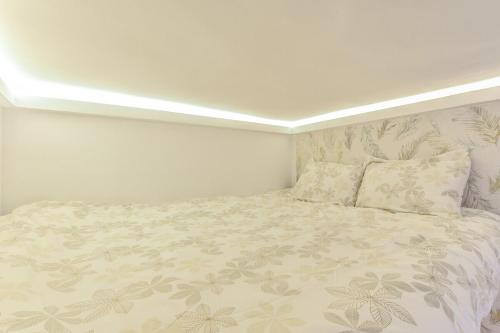 Dormitorio blanco con cama con colcha de flores en MyHouseSpain - Acogedor loft en pleno barrio de La Latina, en Madrid
