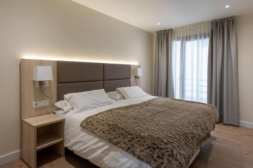 a bedroom with a large bed and a large window at Hotel SAIOLA in Camprodon