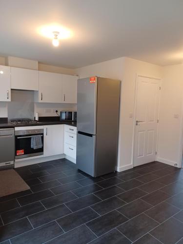 a kitchen with a refrigerator and a tile floor at Spacious Ensuite King Room Private Neighbourhood Free Parking Space in Oldham
