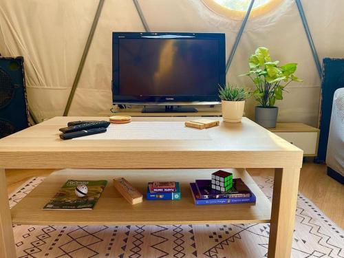 a wooden table with a tv and a table with a table at Olive Dome - כיפה גיאודזית ענקית ומודרנית בין עצי הזית in Yavneʼel
