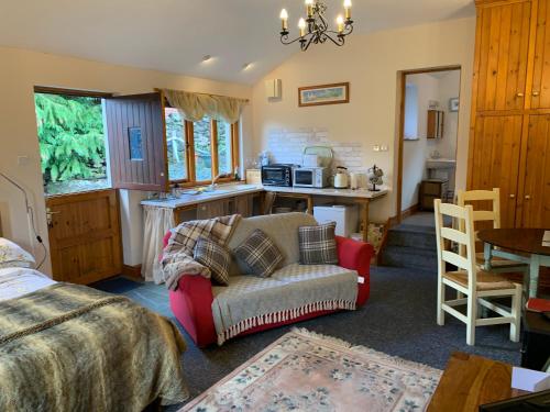 a bedroom with a bed and a couch and a kitchen at Stybeck Farm in Thirlmere
