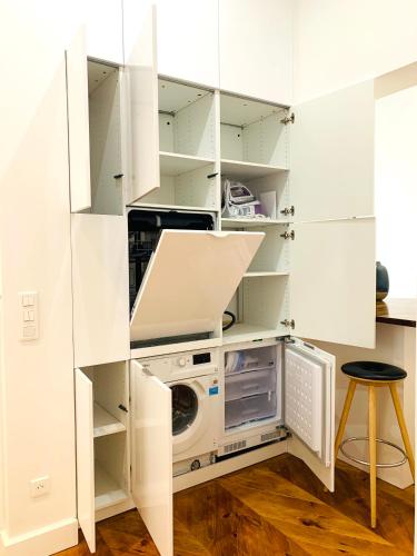 une cuisine avec des armoires blanches et une laveuse et une sécheuse dans l'établissement 2 bedrooms - Paris centre - Champs Elysees, à Paris