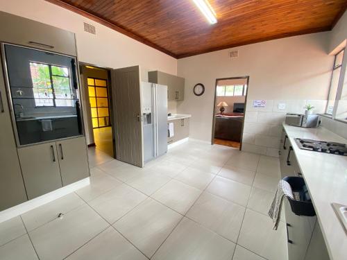 a large kitchen with white appliances and a wooden ceiling at Oost Street in Polokwane