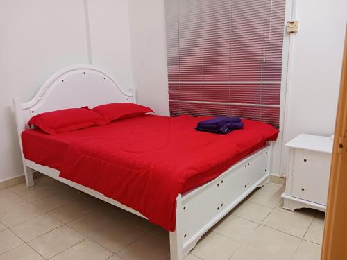 a white bed with red pillows and a red blanket at DSAF Family Homestay Pandan Indah in Ampang