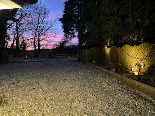 a driveway with a fence and a sunset in the background at Da Vinci Guest House & Guest Parking, A Real Gem in Crawley