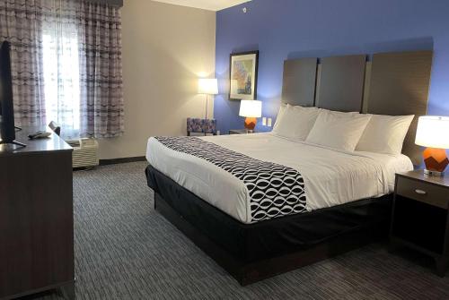 a hotel room with a large bed with white sheets at La Quinta Inn and Suites by Wyndham - Schertz in Schertz