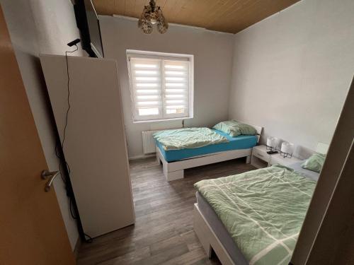 Habitación pequeña con 2 camas y ventana en Ferien- und Monteurunterkunft Alsdorf en Alsdorf