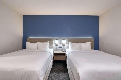 two beds in a hotel room with a blue wall at Comfort Suites Milwaukee Airport in Oak Creek