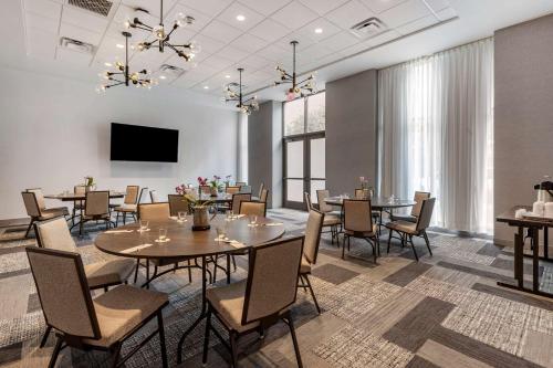 a dining room with tables and chairs and a flat screen tv at Cambria Hotel Savannah Downtown Historic District in Savannah