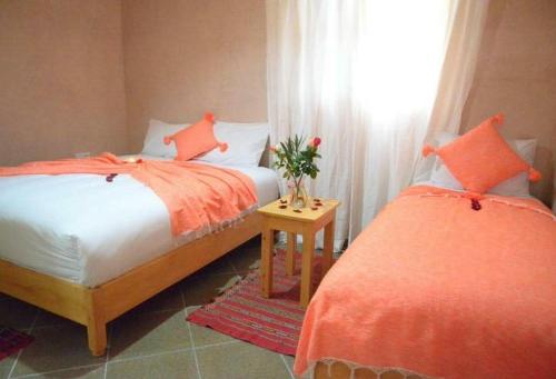 - une chambre avec 2 lits avec des draps orange et une fenêtre dans l'établissement Riad Essaouira, à Essaouira