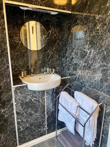 Newcastle Arms Hotel في كولدستريم: حمام مع حوض ومرآة