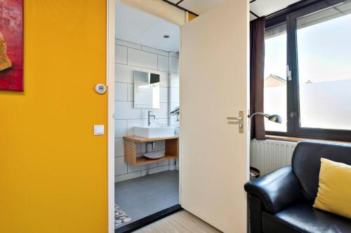 a bathroom with a sink and a black leather couch at Vakantie studio Eijsden in Eijsden