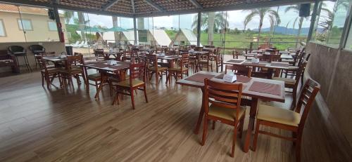a restaurant with wooden tables and chairs and windows at Chalezinho Pousada in Brumadinho