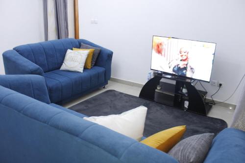 un soggiorno con divano blu e TV di Cozy Bay a Douala