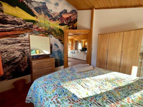 1 dormitorio con 1 cama y una pintura en la pared en Reeds Lodge, Lake Pochard, en South Cerney