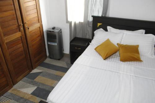 ein Schlafzimmer mit einem weißen Bett und gelben Kissen in der Unterkunft Cozy Bay in Douala