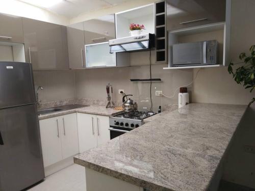 a kitchen with white cabinets and a granite counter top at Centro Cusco Inti in Cusco