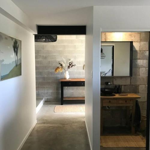 a bathroom with a sink and a table with a mirror at Palm Springs Vibe - Gorgeous Large Home, Superb Location in Noosa Heads
