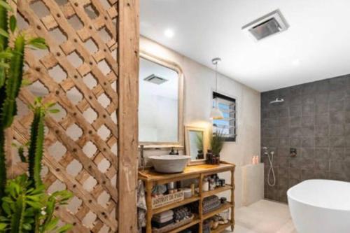a bathroom with a tub and a sink and a mirror at LA Inspired, Gorgeous Spacious Family Home, Superb Location in Noosa Heads