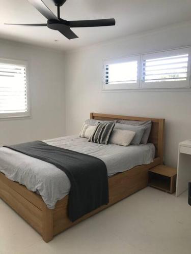 a bedroom with a bed with a ceiling fan at Palm Springs Vibe - Gorgeous Large Home, Superb Location in Noosa Heads