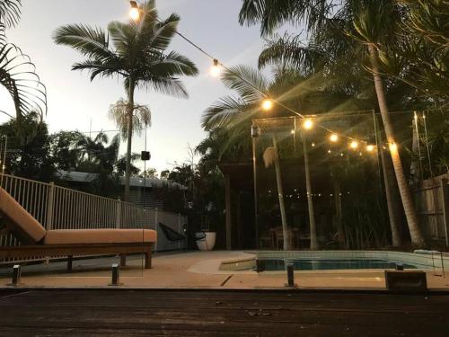 a swimming pool with a bench and palm trees at LA Inspired, Gorgeous Spacious Family Home, Superb Location in Noosa Heads