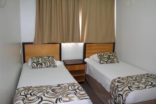a hotel room with two beds and a window at Golden Suíte Hotel in Campinas
