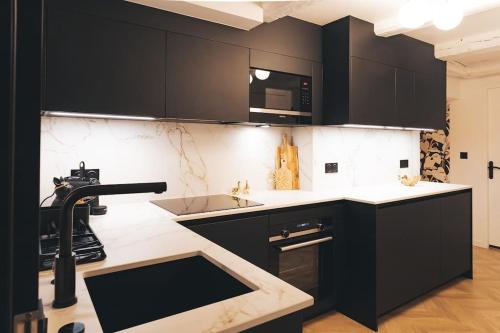 eine Küche mit schwarzen Schränken und einem Waschbecken in der Unterkunft Le Petit Martray - Au coeur du centre ville in Lamballe