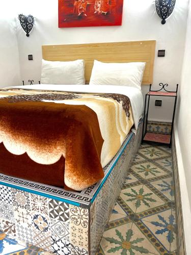 a bedroom with a bed with a tiled floor at Riad chez brahim in Essaouira