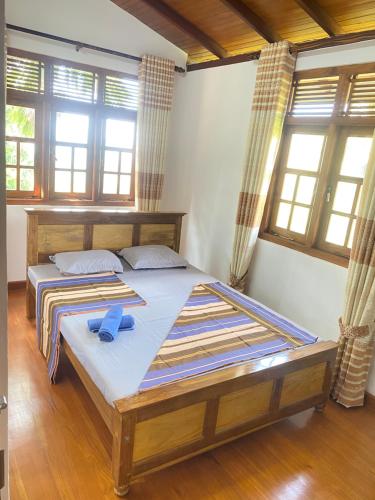 a bedroom with a large bed with blue slippers on it at Happy Feet Diyaluma in Koslanda