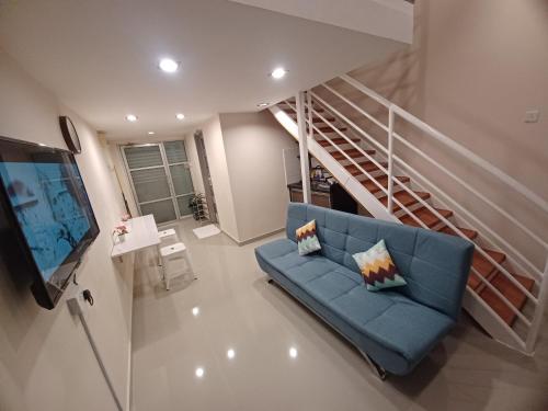 a living room with a blue couch and a staircase at SY Staycation - Studio in Bayan Lepas