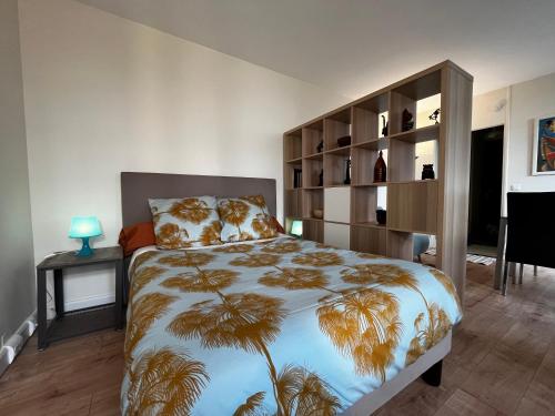 - une chambre avec un lit doté d'un grand couvre-lit avec des palmiers dans l'établissement Spacieux studio sur jardin, beaucoup de charme, à Boulogne-Billancourt