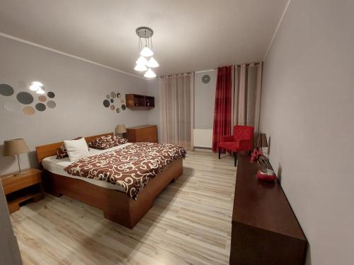 sypialnia z łóżkiem i czerwonym krzesłem w obiekcie SAS Apartamenty "Sapphire" w Szczecinie