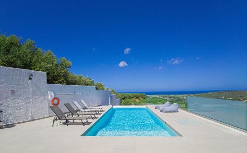 basen z krzesłami i ocean w tle w obiekcie Modern villa with infinity pool close to the sea w mieście Tavronitis