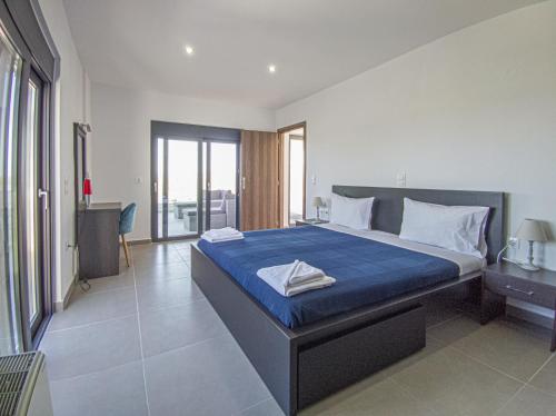 a bedroom with a large bed with a blue blanket at Modern villa with infinity pool close to the sea in Tavronitis