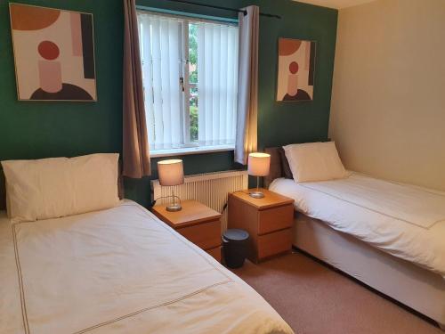 2 camas en una habitación con paredes verdes y ventana en Entire 2 Bedroom Apartment free parking, en Saffron Walden