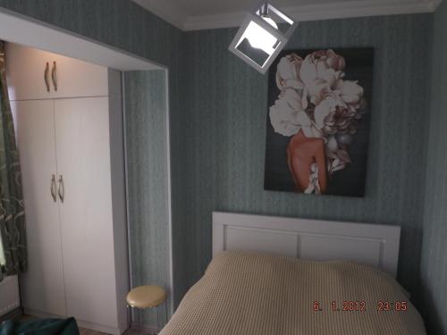 a bedroom with a bed and a painting of flowers at Sweet Home in Kutaisi