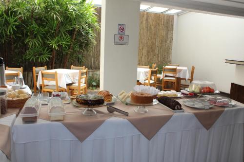 einen Tisch mit Kuchen und anderen Speisen darauf in der Unterkunft Golden Suíte Hotel in Campinas