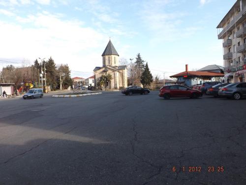 a street with a church and cars parked in a parking lot at Sweet Home in Kutaisi