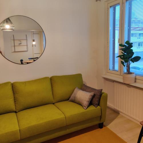 a green couch in a living room with a mirror at Huoneisto rantabulevardilla, 1-4 hengelle in Savonlinna