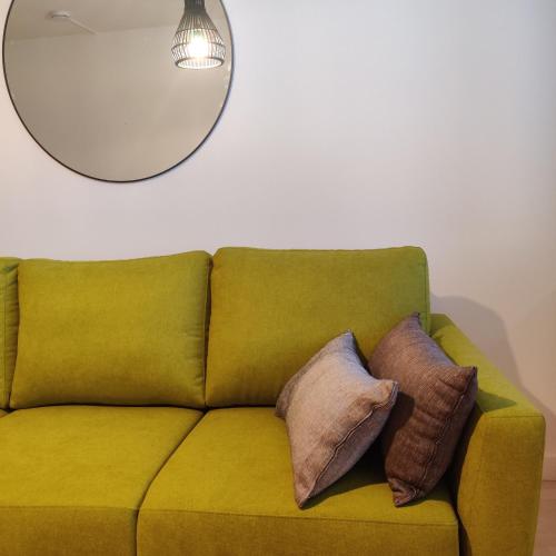 a green couch with pillows on it with a mirror at Huoneisto rantabulevardilla, 1-4 hengelle in Savonlinna