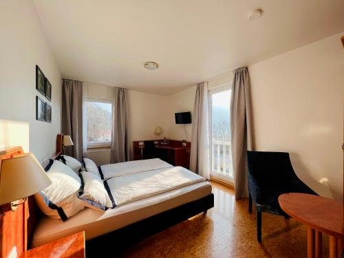 a bedroom with a bed and a table and two windows at TheCrossing Bed & Breakfast in Hausen im Tal