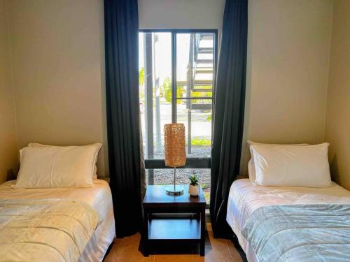 two beds in a room with a window and a table at Modern 2 Bed Apartment - Oaks Resort, Cable Beach in Cable Beach