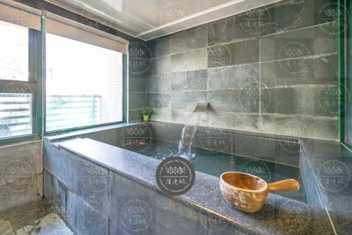 a bathroom with a tub with a bowl on a counter at 泉泉溫泉民宿 in Jiaoxi